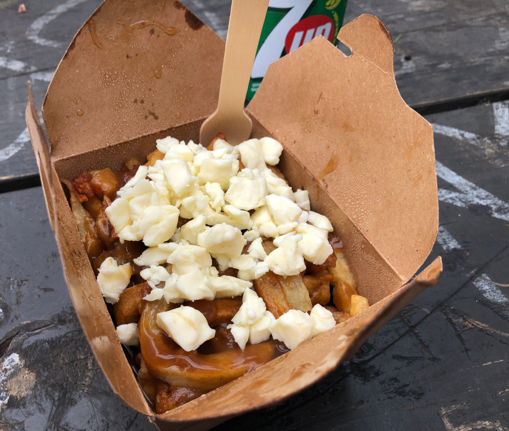 Poutine in a cardboard container on a picnic table